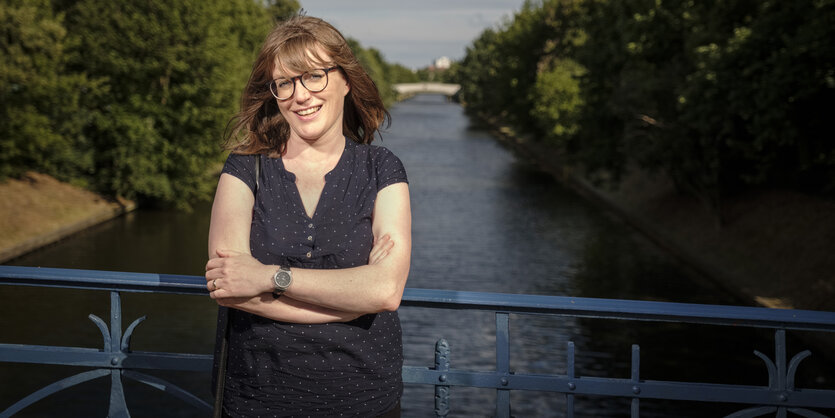 Die Landespolitikerin der Linken, Lucy Redler, steht an einem Geländer, im Hintergrund ist der Schifffahrtskanal in Neukölln zu sehen