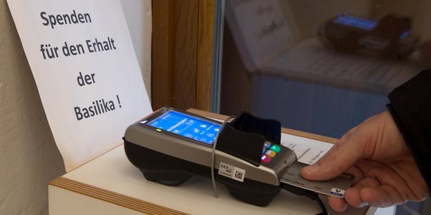 Digitaler Klingelbeutel: eine Mann zahlt die Kollekte mit einer EC-Karte