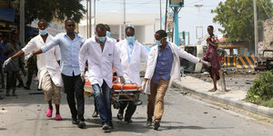 In Mogadishu tragen mehrere Menschen in weißen Kitteln eine Person weg