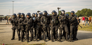 Polizisten mit Schutzkleidung und Helmen stehen dicht beieinander.