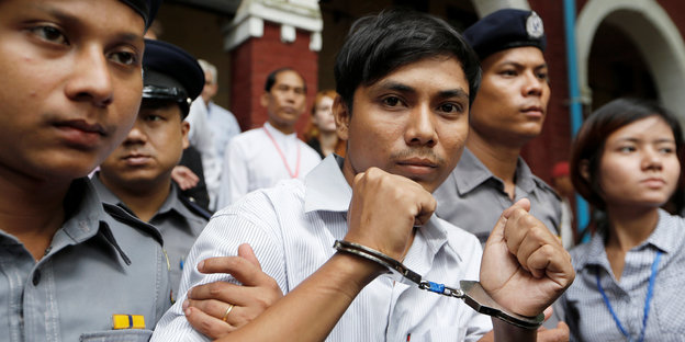 Der Journalist Kyaw Soe Oo ist in Handschellen und wird von Polizisten eskortiert