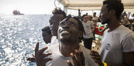 Ein geretteter Flüchtling streckt seine Arme zum Himmel