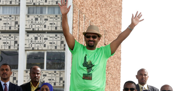 Äthiopiens Premierminister Abiy Ahmed trägt einen Hut und ein grünes T-Shirt und reißt die Arme hoch Äthiopiens Premierminister Abiy Ahmed trägt einen Hut und ein grünes T-Shirt und reißt die Arme hoch
