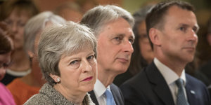 Theresa May sitzt neben Philip Hammond und Jeremy Hunt
