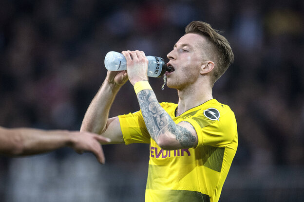 Marco Reus von Borussia Dortmund versucht im Laufen aus einer Flasche zu trinken. Dabei kommt ihm ein Schwall Wasser aus dem Mund.