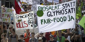 Demonstranten halten Transparente mit den Aufschriften "Syngenta kills" und "Biosalat statt Glyphosat! Fair-Food Ja"