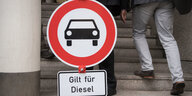Jemand trägt ein Straßenschild, auf dem steht: Gilt für Diesel