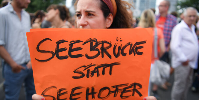 Eine Demonstrantin hält ein Schild, auf dem steht 