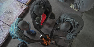 Von Libyen und Italien nicht erwünscht: Afrikanische Flüchtlinge teilen sich eine Schale mit Essen in einem Flüchtlingslager in Tripolis