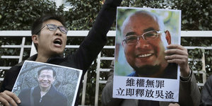 Aktivisten halten Fotos der Regimekritiker Qin Yongmin und Wu Gan hoch