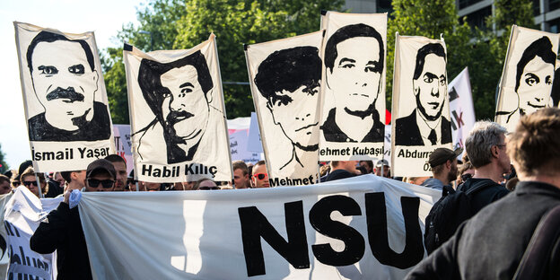 Demonstranten halten bei einer Kundgebung in München Schilder mit Porträt-Abbildungen der NSU-Opfer