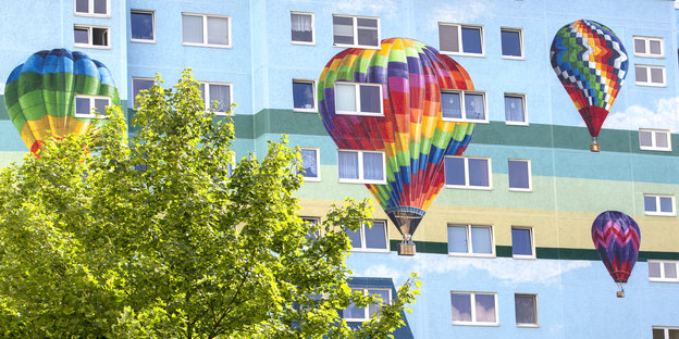 Kunstwerk mit Heißluftballons auf Plattenbaufassade.