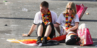 Zwei Fans sitzen nach dem Public Viewing zur WM-Vorrunde Südkorea - Deutschland auf dem Boden.