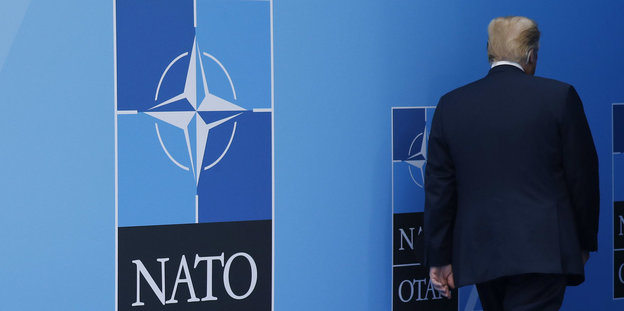 Trump bei der Nato: Links ein Nato-Zeichen, rechts der weggehende US-Präsident