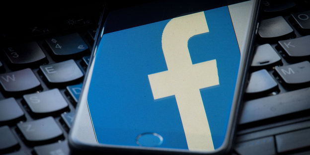 Ein Smartphone mit Facebook-Logo liegt auf einem Laptop