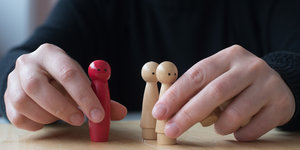 Therapie: Zwei Hände mit drei Holzfiguren