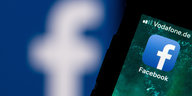 Ein Smartphone mit Facebook-Logo auf dem Bildschirm liegt auf einem Laptop