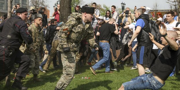 Mitten in einem Protest gegen Putin: Ein Mann in Uniform stößt einen Mann in kurzen Hosen zu Boden