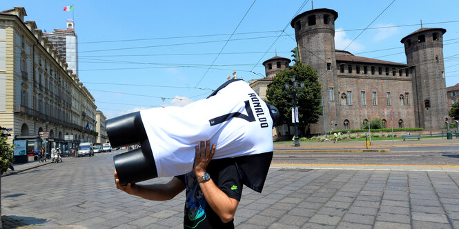 Ein Mann trägt eine Schaufensterpuppe mit einem Trikot von Juve und Ronaldos Namen durch die Straßen von Turin