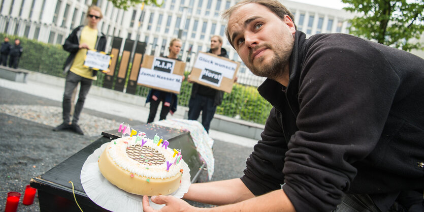 Ein schwarzer Sarg mit einem Geburtstagskuchen oben drauf.