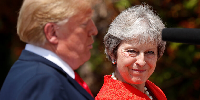 Theresa May schaut Donald Trump von der Seite an. Ihr Gesichtsausdruck ist kritisch-belustigt