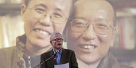 Ian Johnson hält eine Rede für Liu Xiaobo - vorne ein Mann mit einem Zettel, hinten an die Wand projiziert ein Mann und eine Frau - Liu Xia und Liu Xiaobo