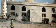 Ein junger Mann läuft vor einer teilweise zerstörten Moschee vorbei