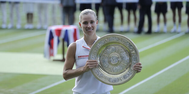Die Tennisspielerin Angélique Kerber mit der Siegerinnenschale von Wimbledon - sie lächelt glücklich