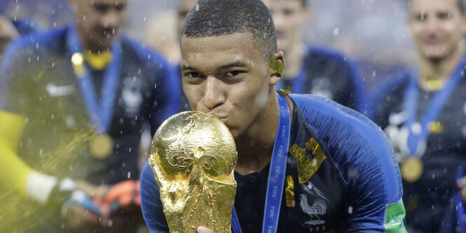 Frankreichs Fußballnationalspieler Kylian Mbappé küsst die Fifa-Trophäe nach dem Sieg im WM-Finale