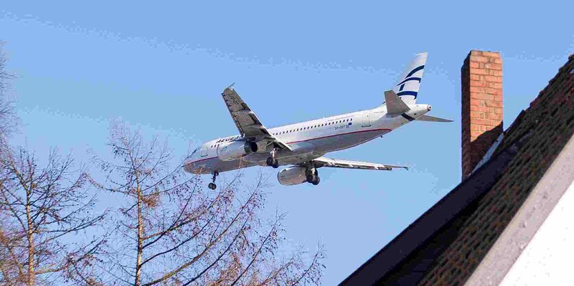 Ein Flugzeug fliegt über dem Dach eines Hauses.