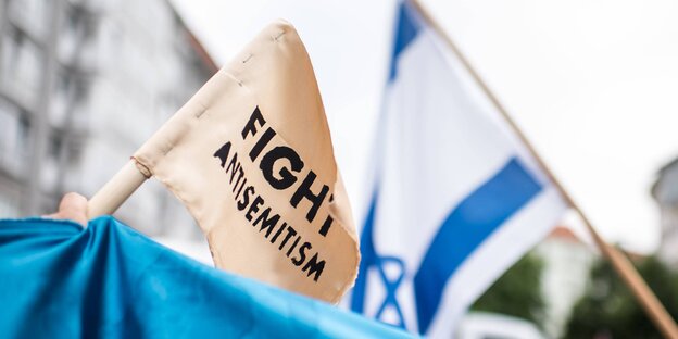 Eine Israel-Flagge und eine weiße Flagge, auf der "Fight Antisemitism" steht