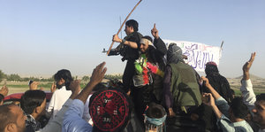 Taliban-Kämpfer winken, einer schwenkt eine weiße Fahne
