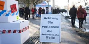 Wenige Meter vor einem AfD-Zelt steht ein Aufsteller mit der Aufschrift: Achtung, Sie verlassen die demokratische Meile