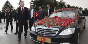 ein Mann läuft neben einem Auto her, das mit roten Rosen bestreut ist