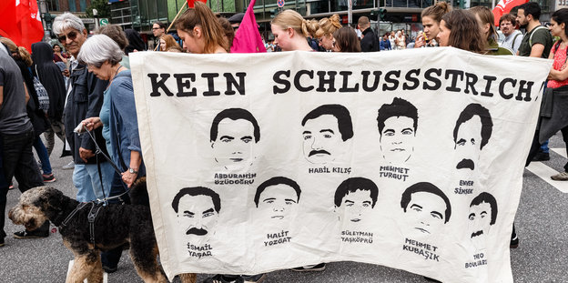 Demonstranten mit einem Plakat auf dem „Kein Schlussstrich“ steht