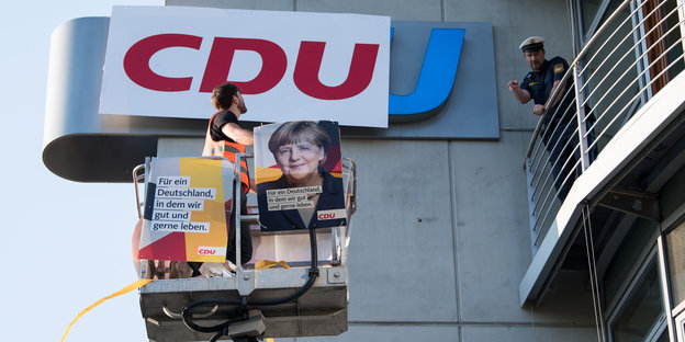 Ein Demonstrant bringt ein Logo der CDU mit einer Hebebühne an der CSU-Zentrale an.