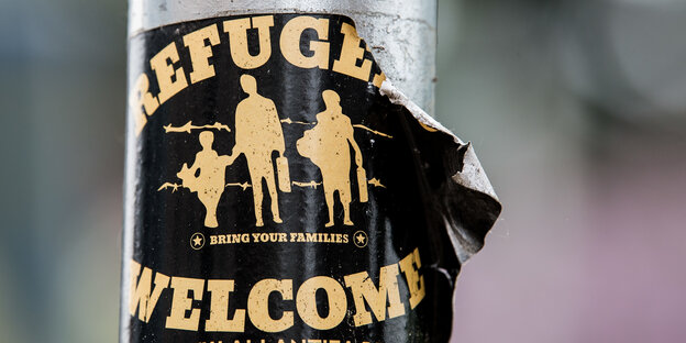 Ein Aufkleber mit der Aufschrift "Refugees welcome" klebt an einem Laternenmast