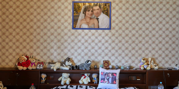 An der Wand über dem Bett hängt ein Hochzeitsfoto, auf dem Bett liegen viele Kuscheltiere An der Wand über dem Bett hängt ein Hochzeitsfoto, auf dem Bett liegen viele Kuscheltiere
