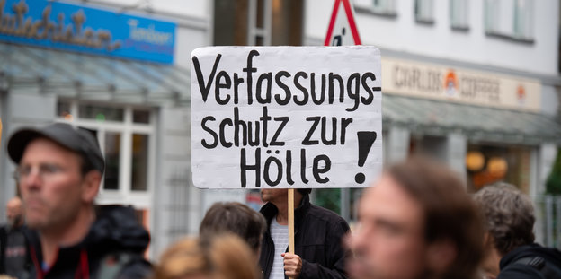 Ein Demonstrant trägt ein Schild mit der Aufschrift "Verfassungsschutz zur Hölle!".