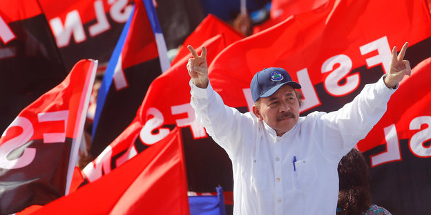 Vor den schwarz-roten Fahnen der FSLN macht Nicaraguas Präsident Daniel Ortega das Victory-Zeichen