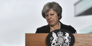 Theresa May mit grimmigem Gesicht hinter einem Stehpult