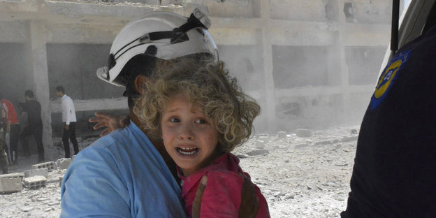 Einer der Weißhelme trägt ein Kind nach einem Luftangriff in Syrien