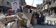 Soldaten sitzen an einem selbstgebauten Unterstand, vor dem ein Porträt von Assad aufgestellt ist