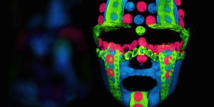 Das Gesicht eines Menschen mit bunten, leuchtenden Farben angemalt