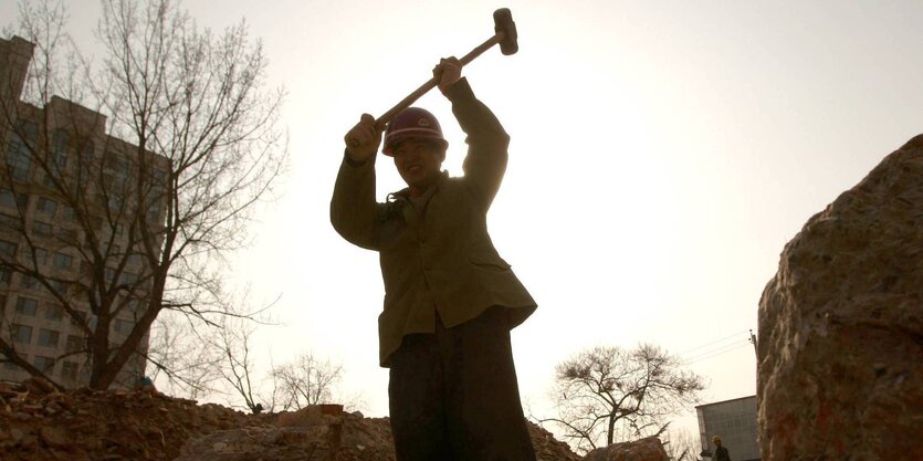 Ein Mensch zerschlägt etwas mit einem Hammer