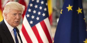 Donald Trump vor Fahnen der USA und EU