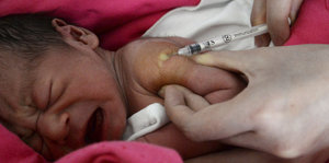 Baby wird mit einer Spritze in die Schulter geimpft
