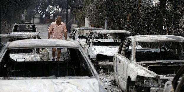 Ein Mann geht an verbrannten Autos vorbei