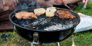 Steaks liegen auf einem Holzkohlegrill