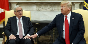 Trump und Juncker sitzen nebeneinander; Trump legt Juncker seine Hand aufs Knie